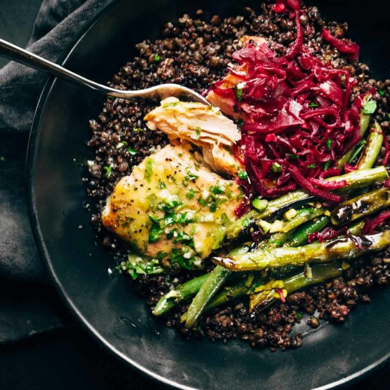 Baked salmon with lentils, green beans, and sauerkraut in bowl.