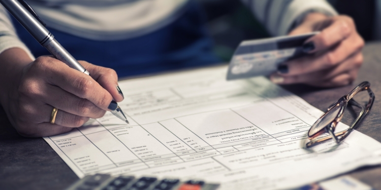 Person reviewing a bank account statement with a bank card in their hand