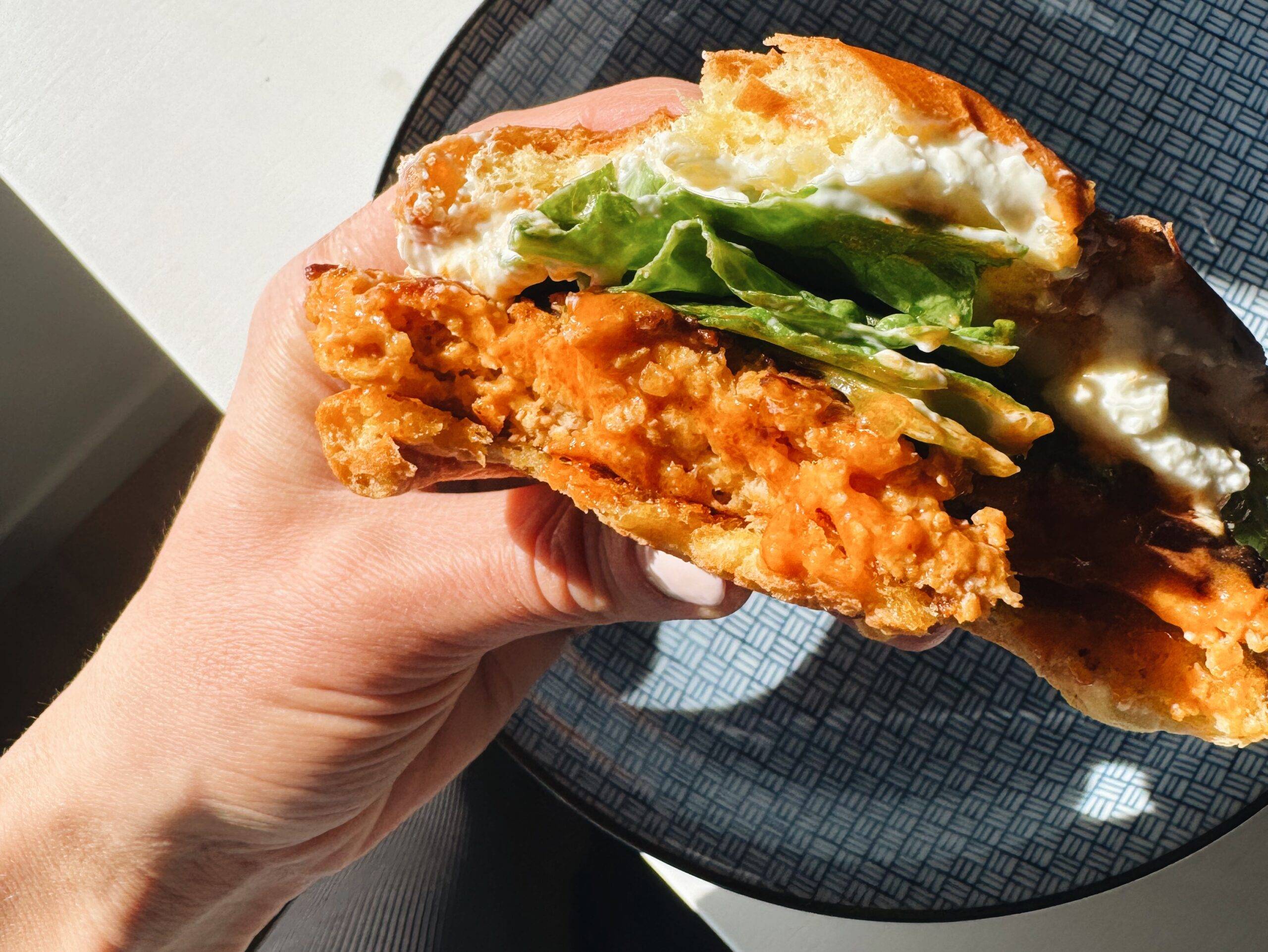 Hand holding a buffalo chicken burger.