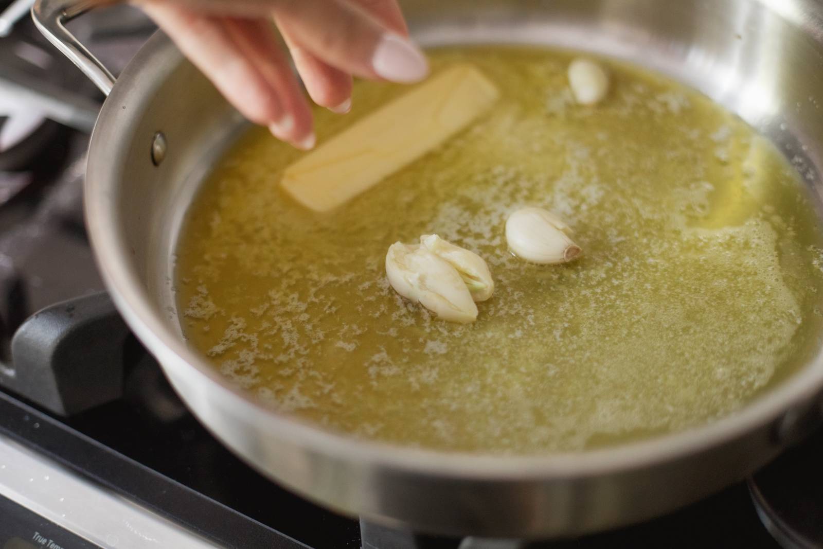 Sautéing butter and garlic cloves in a pan.