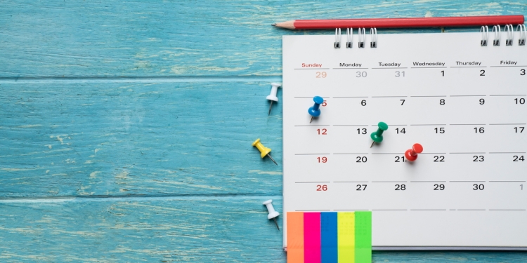 Calendar with pins and notes on a blue wooden table