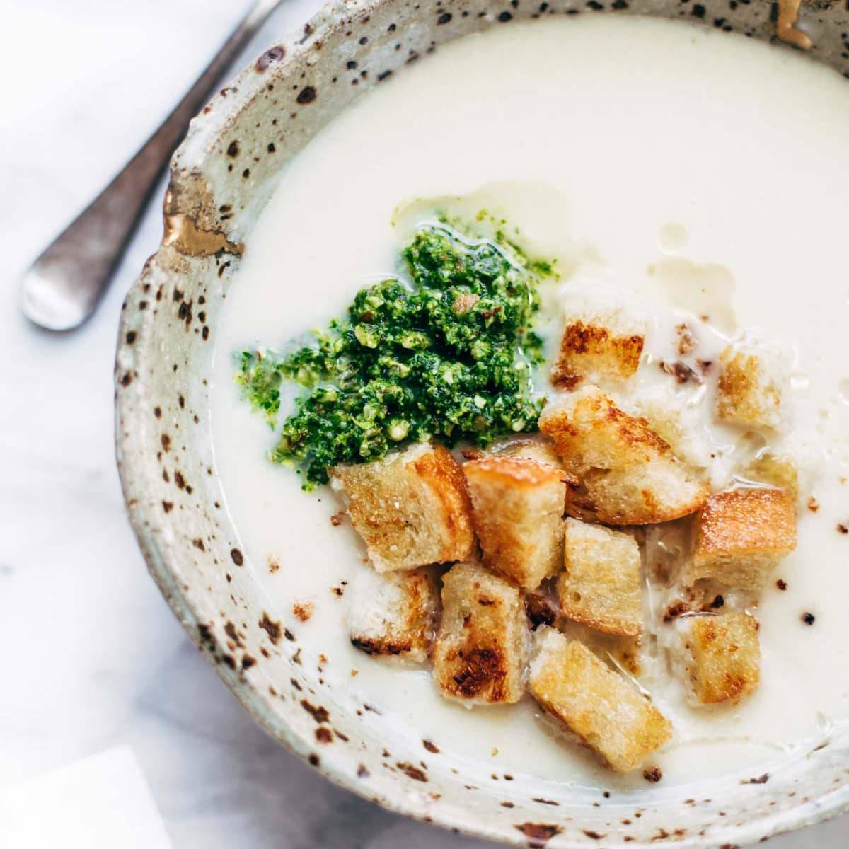 Cheesy Cauliflower Soup in a bowl with pesto and croutons.