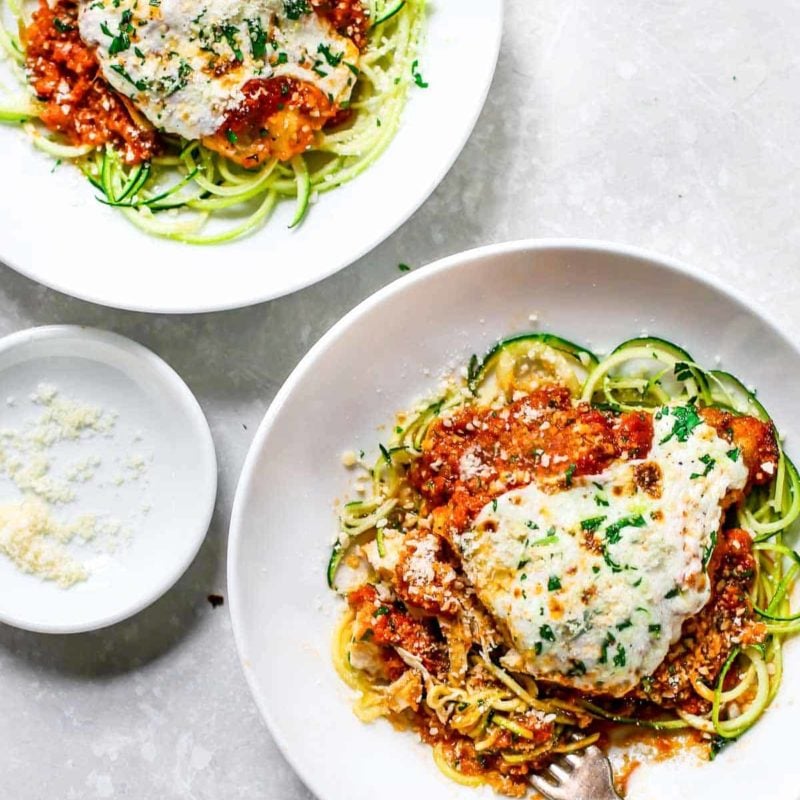 Chicken parmesan on a plate of zucchini noodles.