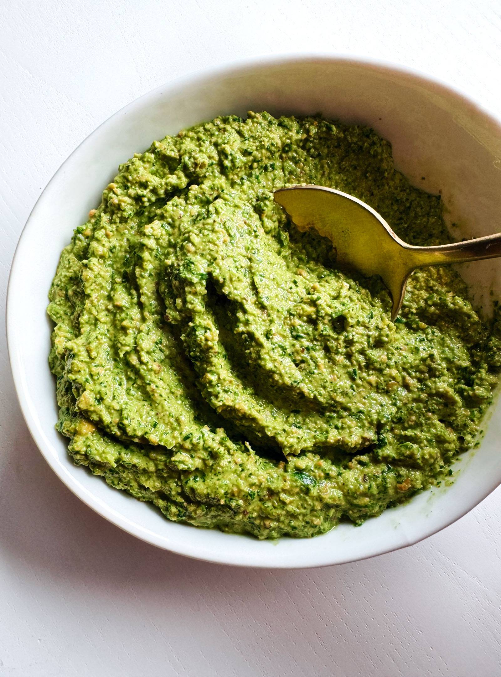 Cilantro pesto in a bowl with a spoon.