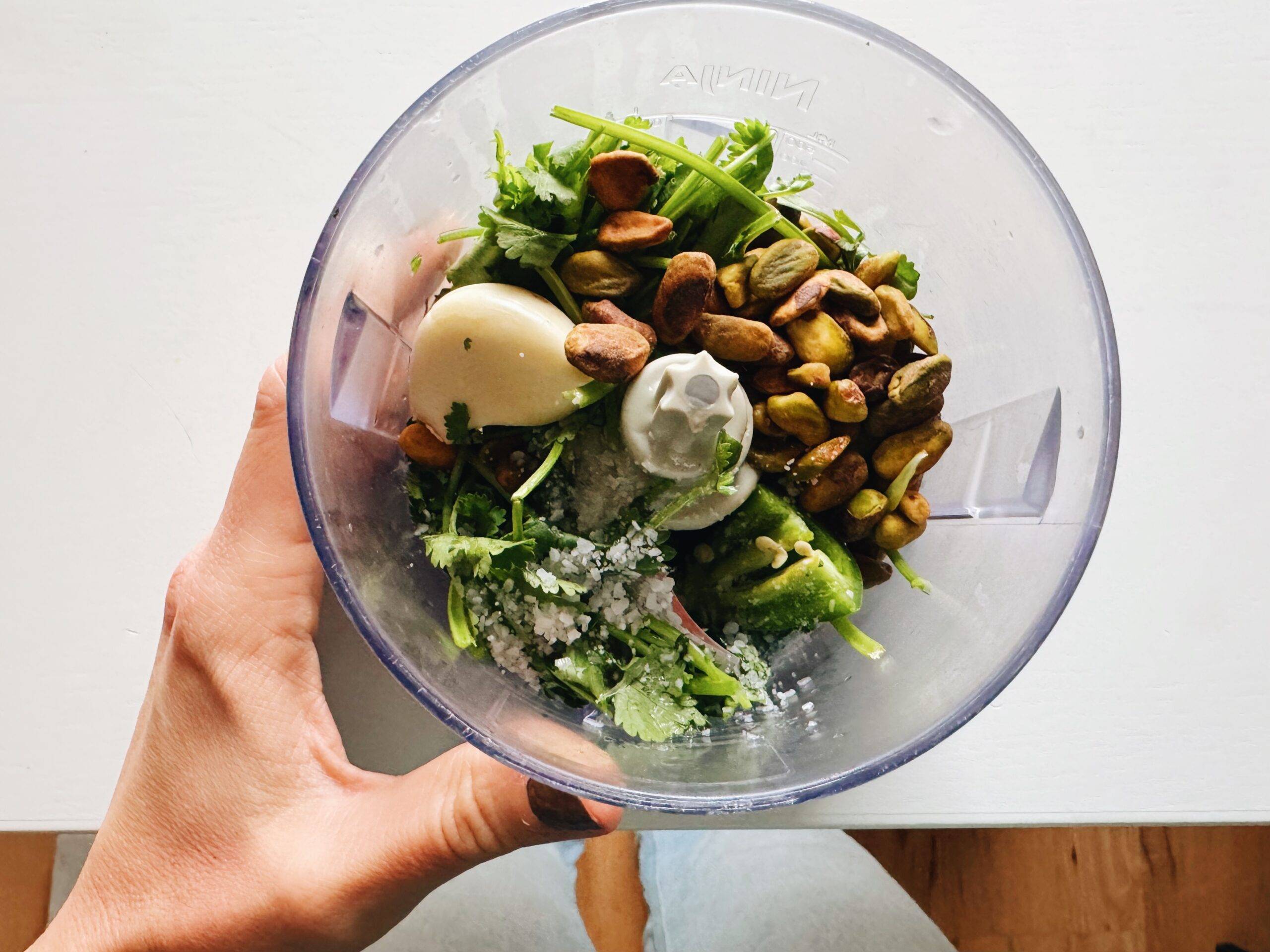 Blending cilantro pesto in a food processor.