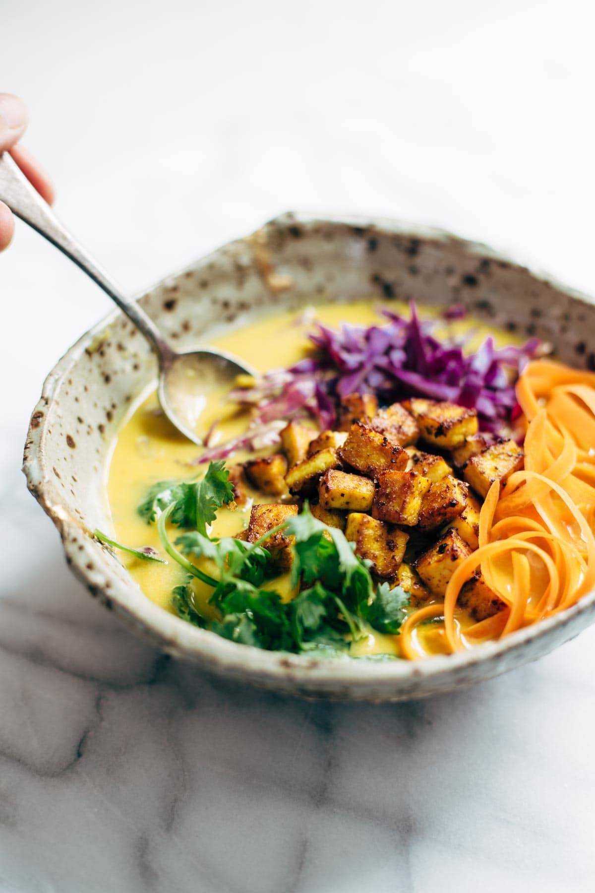 Bowl of coconut curry soup with tofu on top.