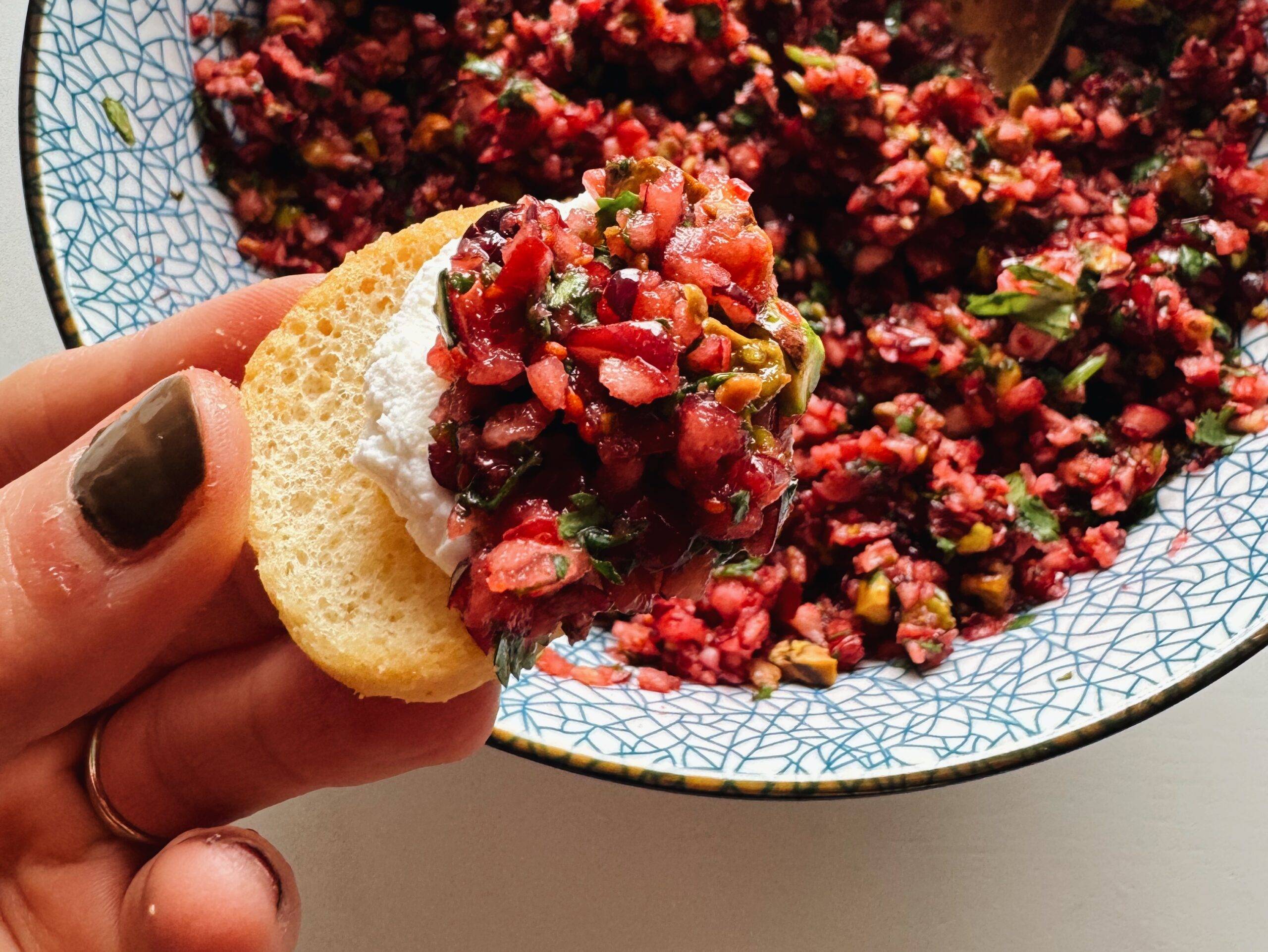 Crostini dipping up cream cheese and cranberry salsa.