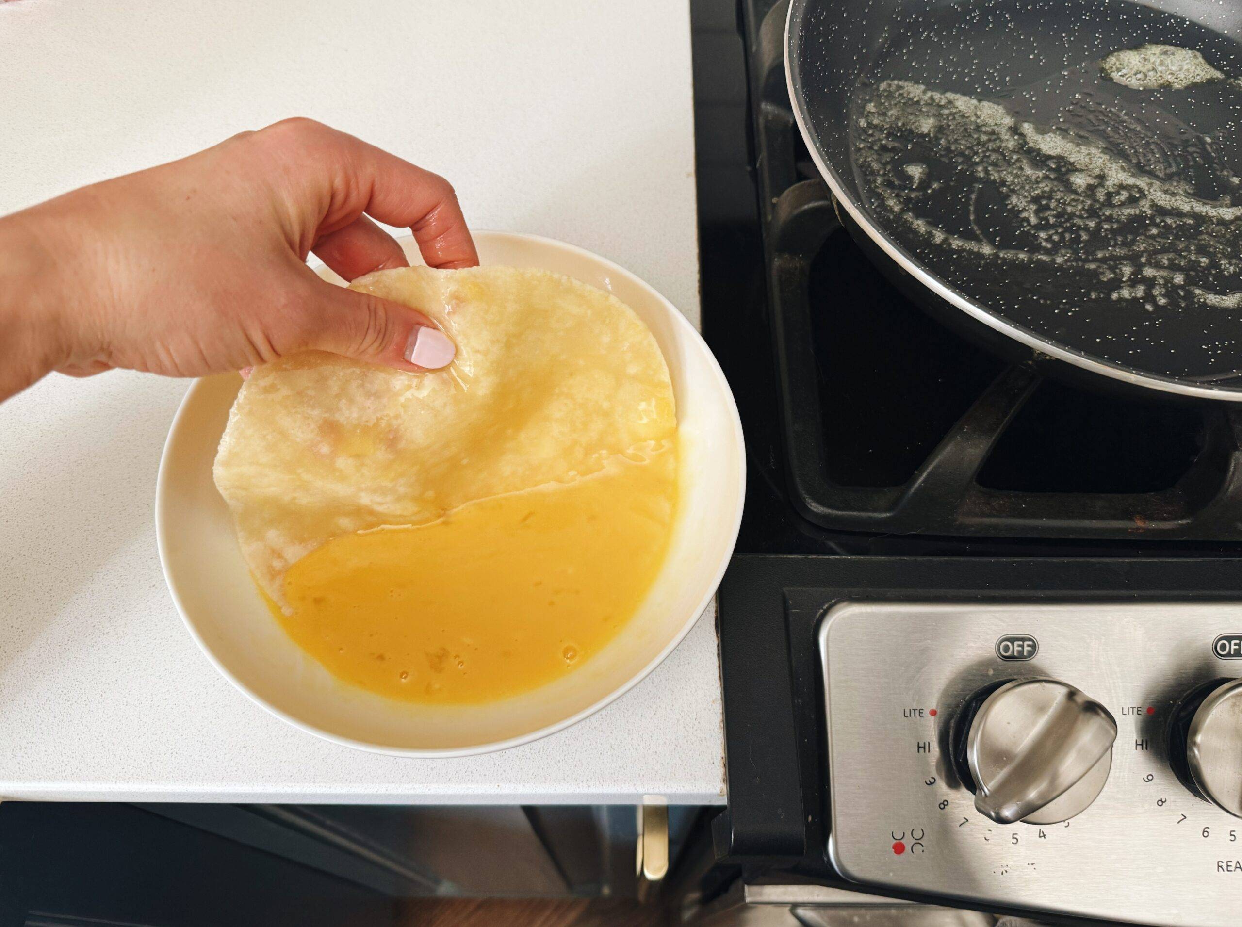 Dipping almond flour tortilla into egg mixture.