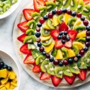 Fruit pizza with bowls of fruit.