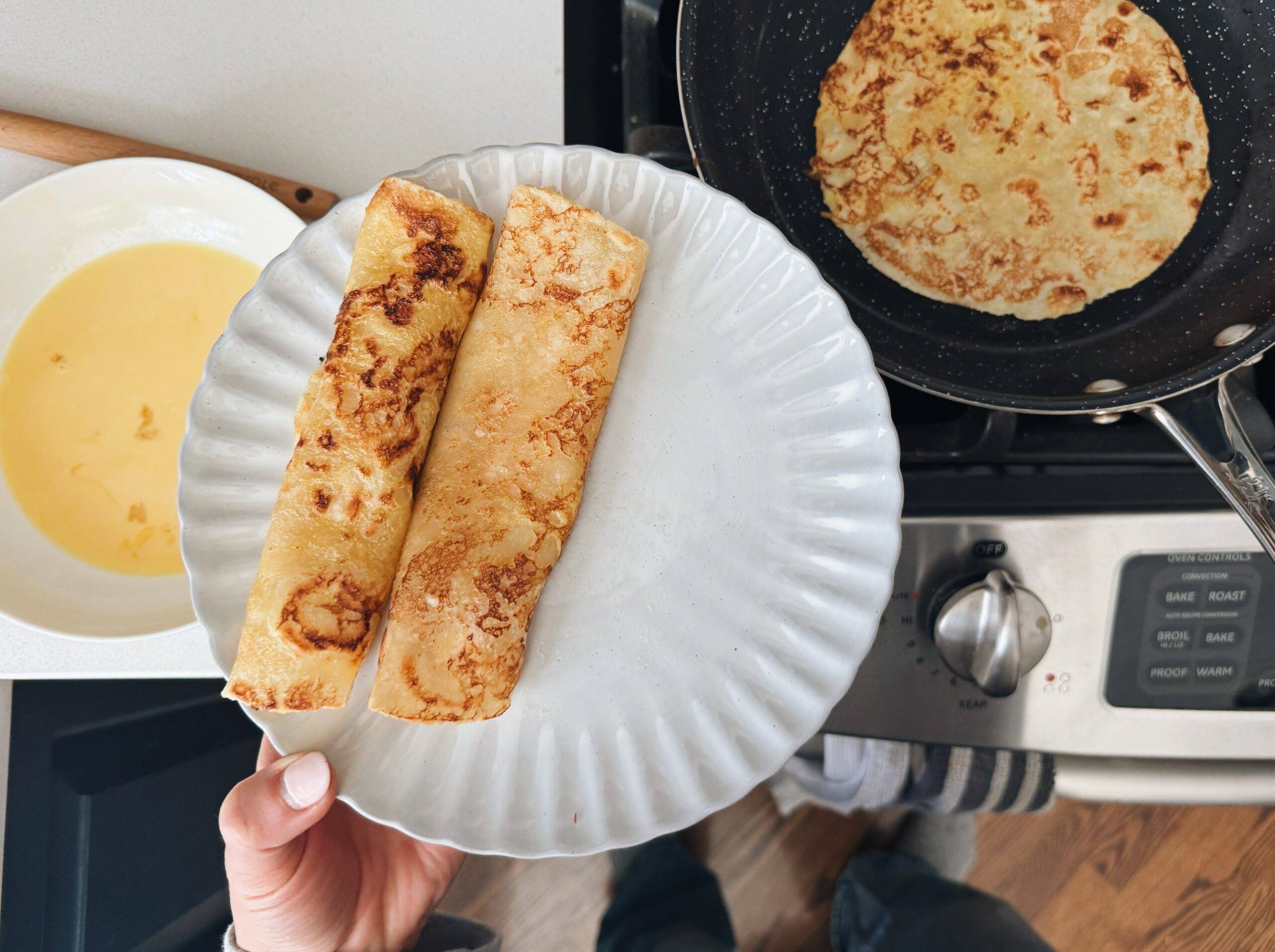 Rolled french toast crepes on a plate.