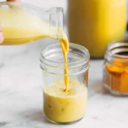 Golden latte being poured from a jar into another jar.