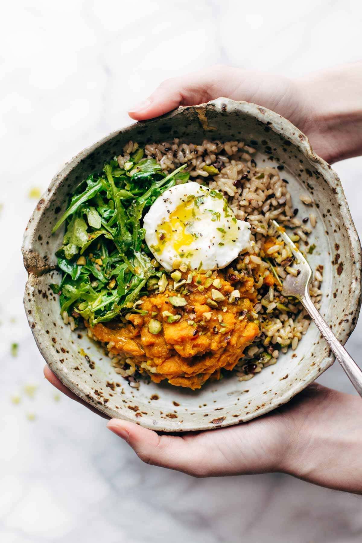 Bowl of sweet potatoes and brown rice with an egg and a fork.