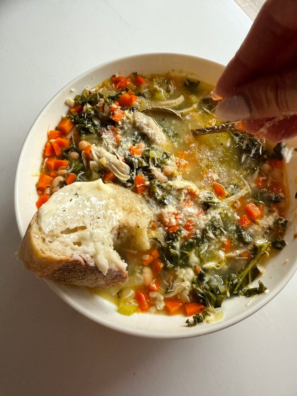 Lemon rosemary chicken soup in a bowl with buttered bread.