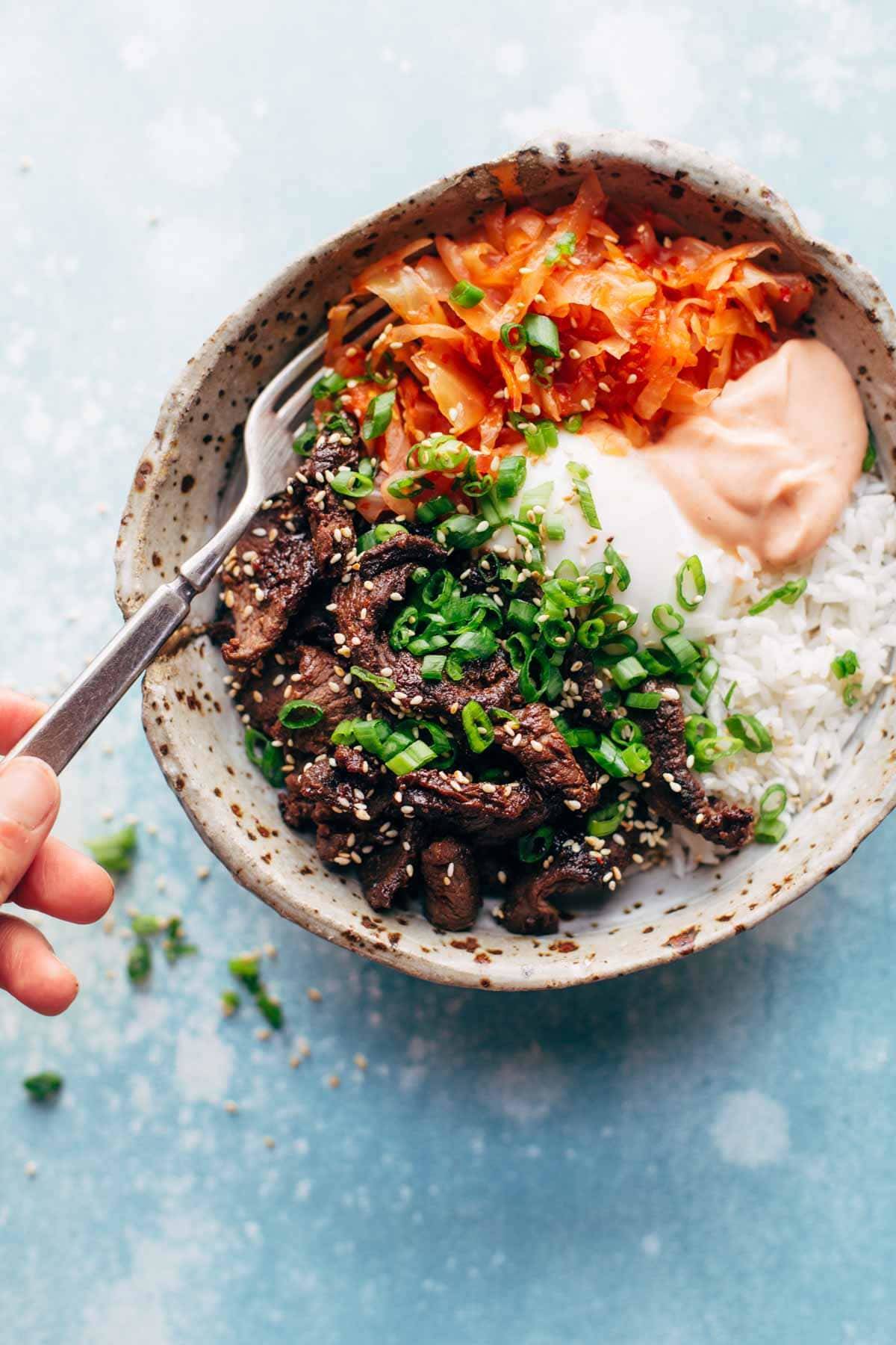 Bowl with rice and steak with a fork.