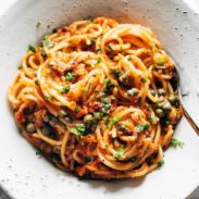 Pasta puttanesca in a white bowl.