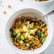 Spiralized veggies in a bowl with chickpeas and green sauce.