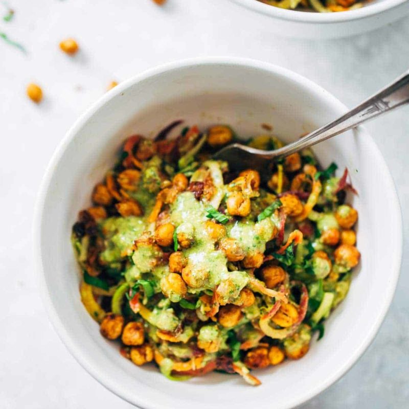 Spiralized veggies in a bowl with chickpeas and green sauce.