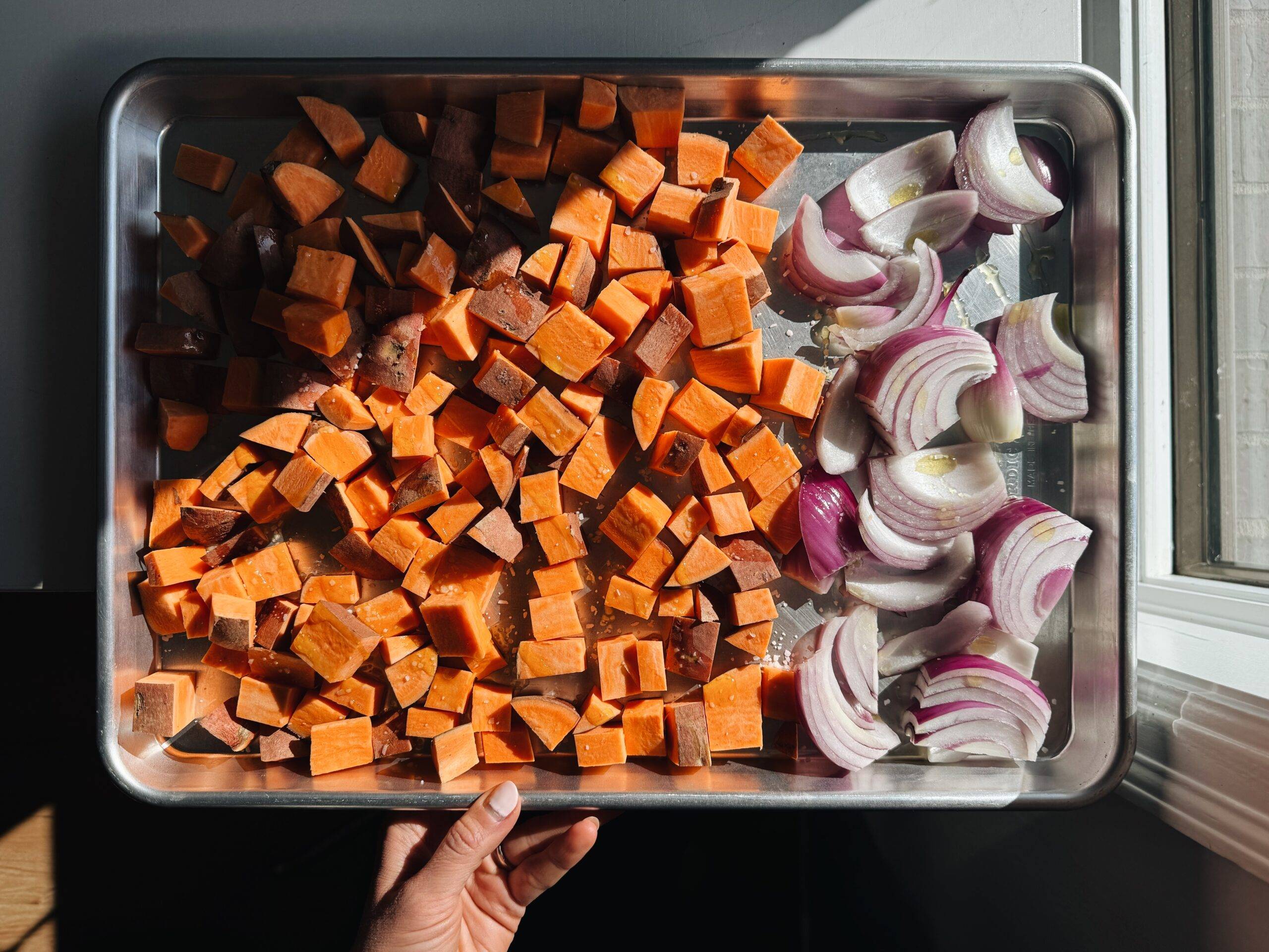 Sweet potatoes and onions on a sheet pan.