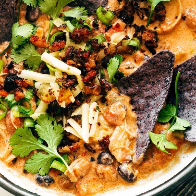 Chips in a bowls of chili and garnishments.