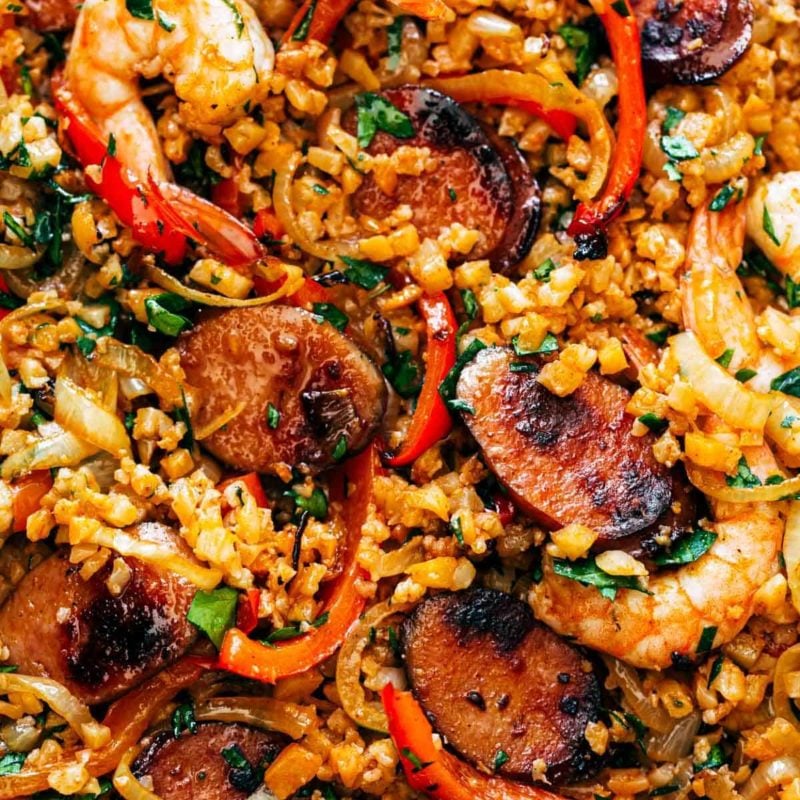 Cauliflower rice and meats arranged together on a sheet pan.