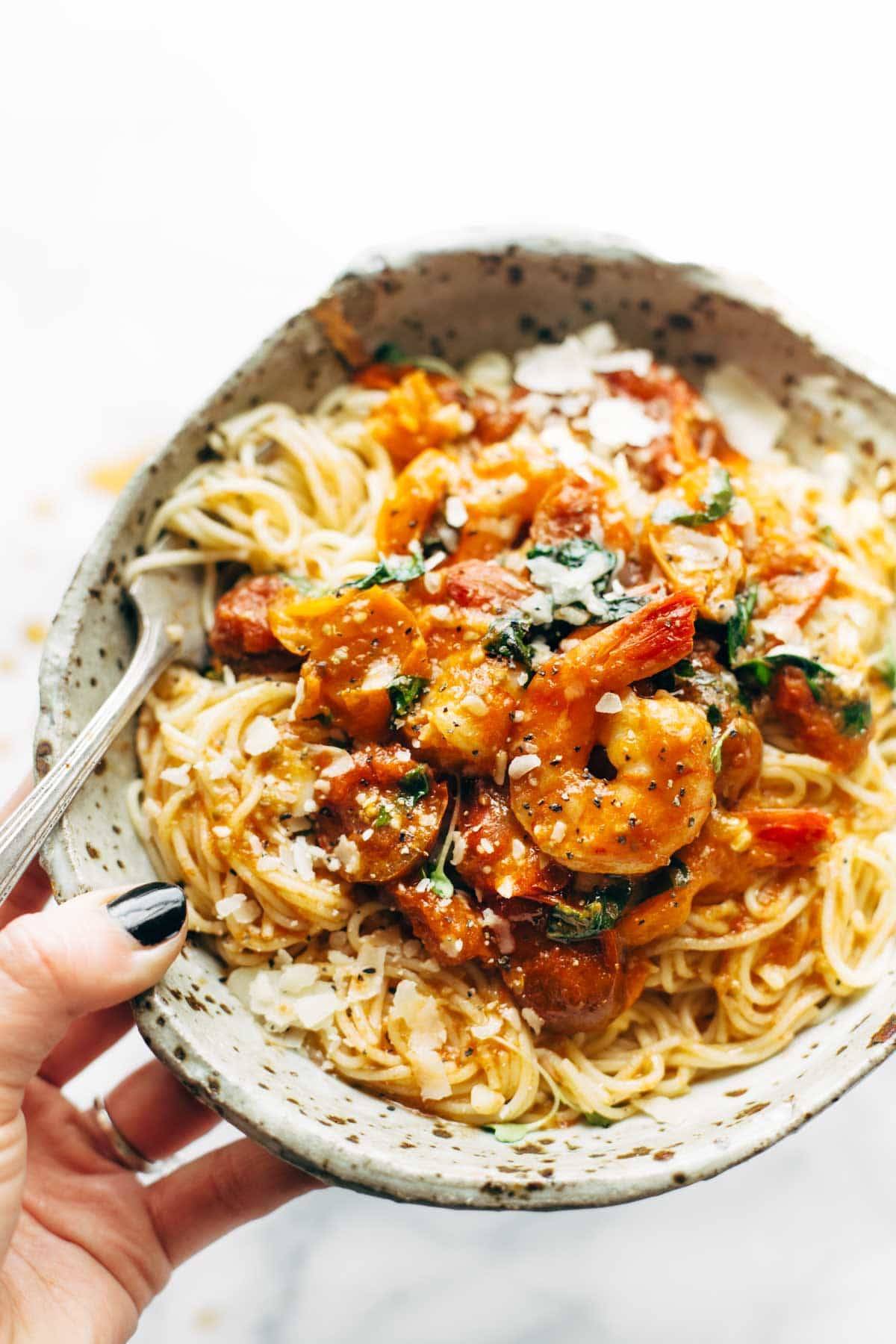 Capellini pomodoro with shrimp in a bowl with a spoon.