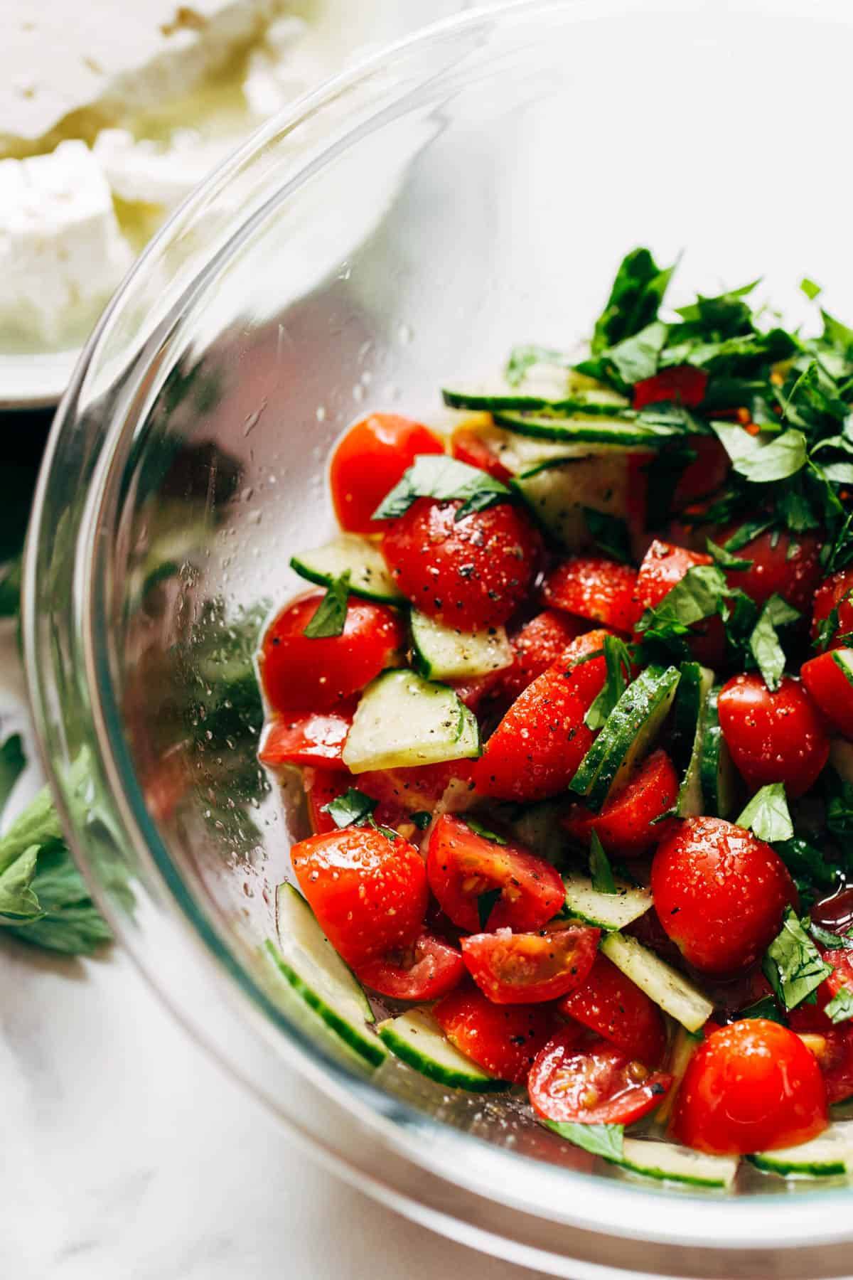 Feta and Tomato Salad in a clear bowl sitting on a countertop.