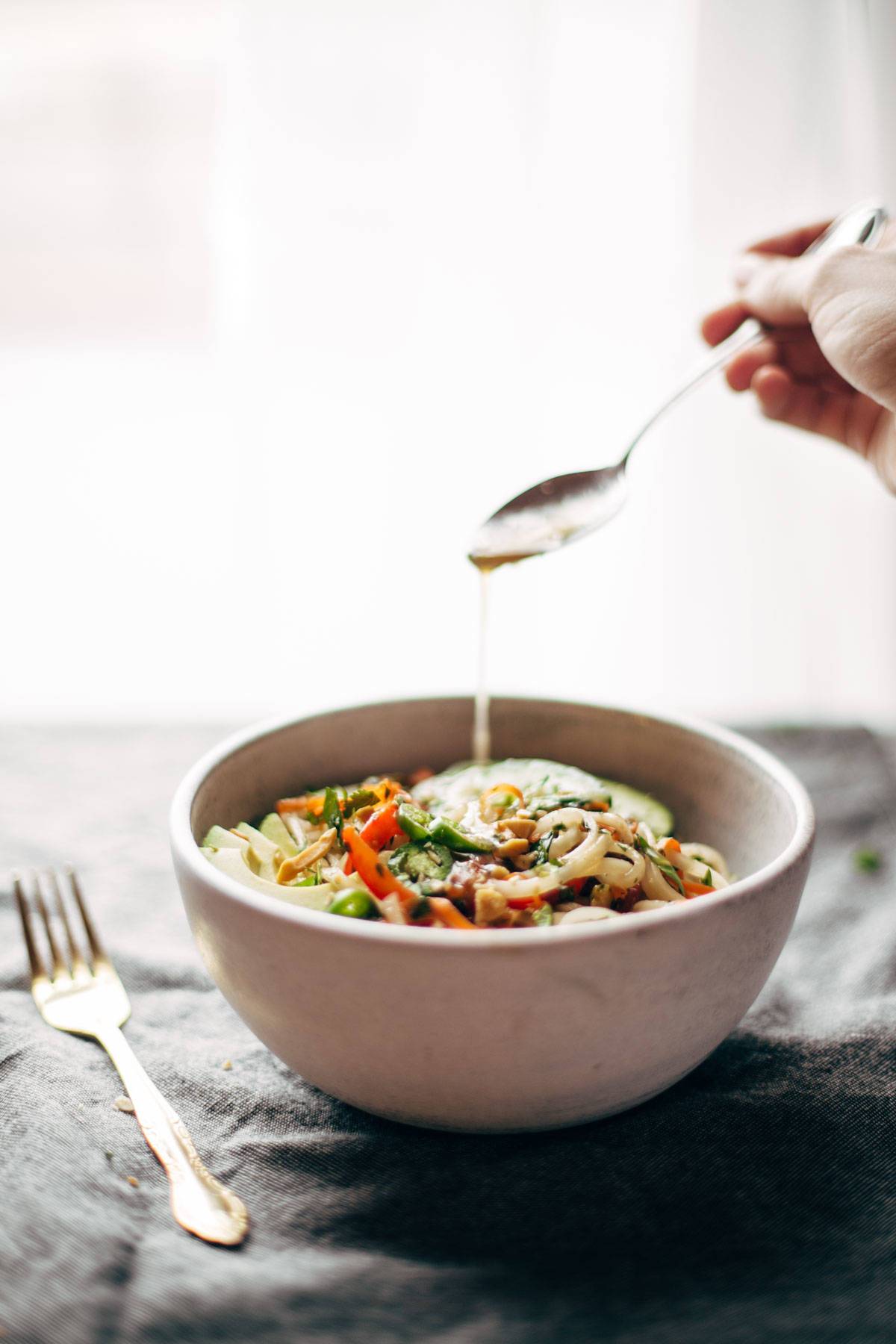 Spring roll bowl with a drizzle of sauce with a spoon and a fork.