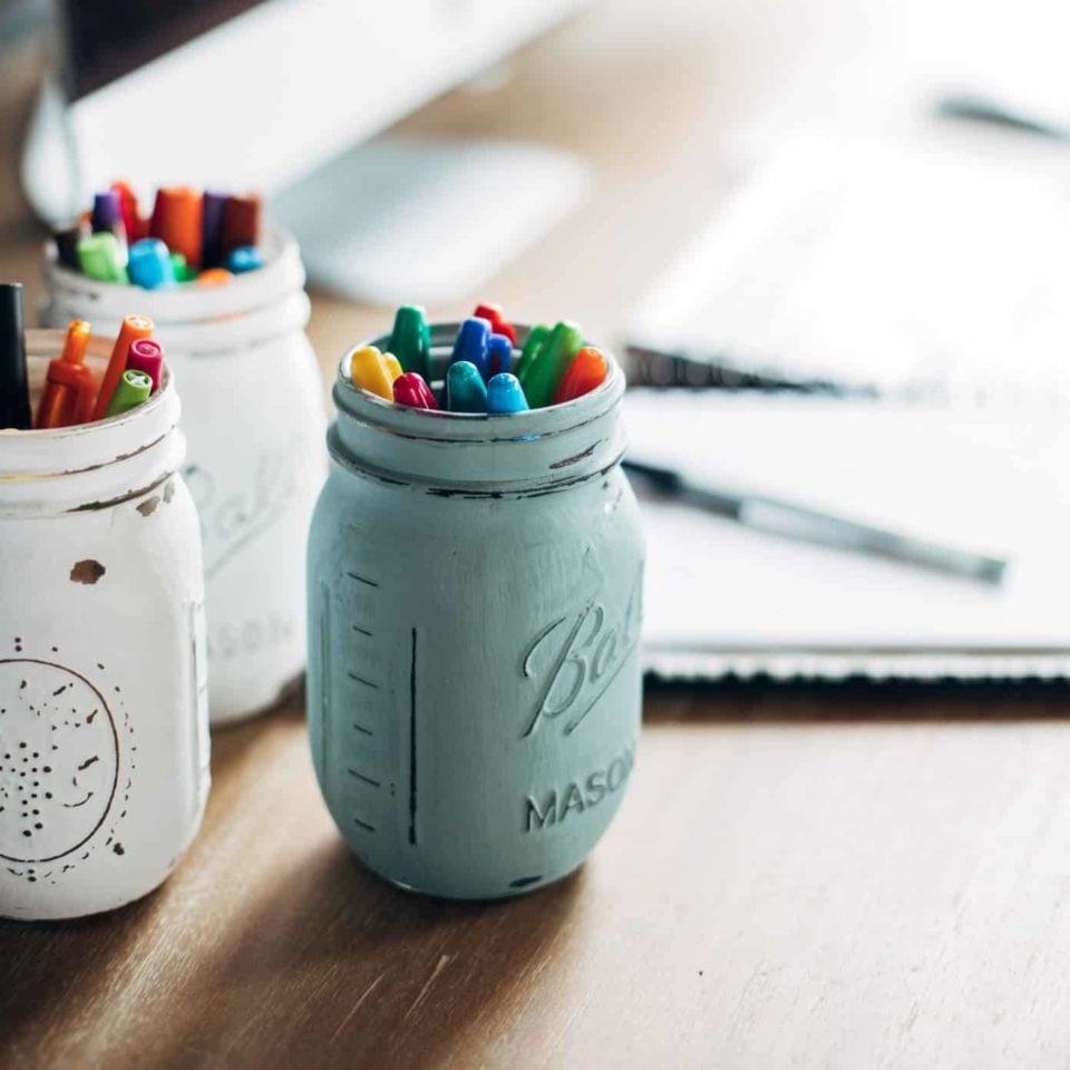 Pens sitting in jars on a desk.