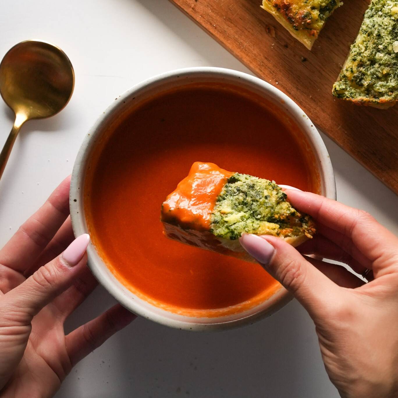 Tomato soup in a bowl with garlic bread dipped in.